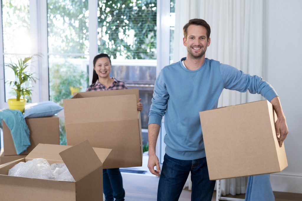 Couple carrying big cardboard box at new home