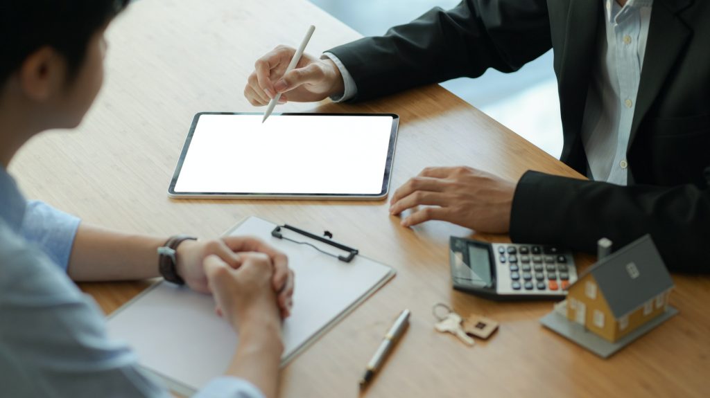 Insurance agents with tablet are introducing real estate insurance programs for customer.