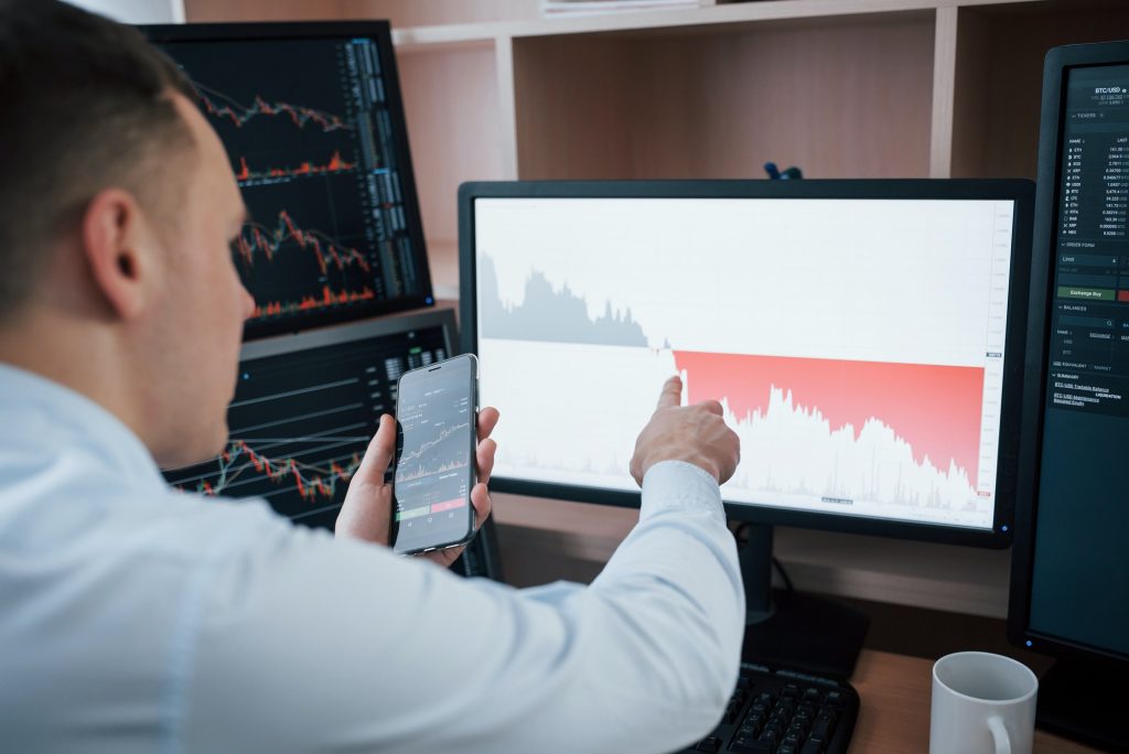 Man working online in the office with multiple computer screens in index charts